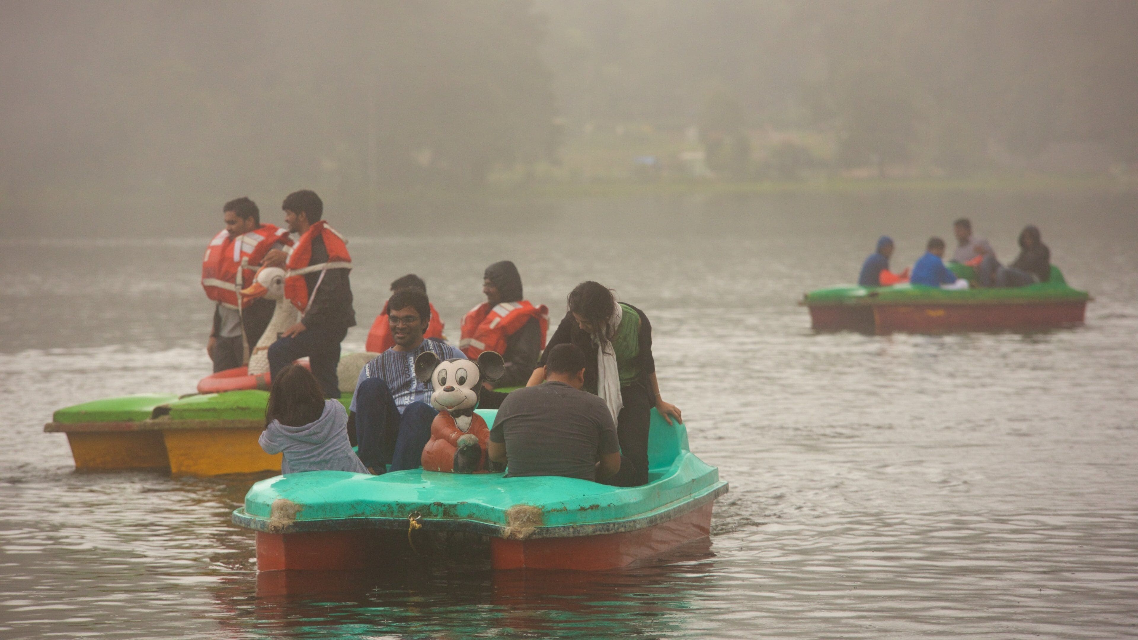People on small boats on a foggy lake.