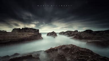 A coastal landscape with rocky formations and a misty atmosphere.