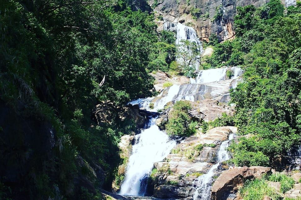A waterfall cascading over rocky terrain surrounded by dense greenery.