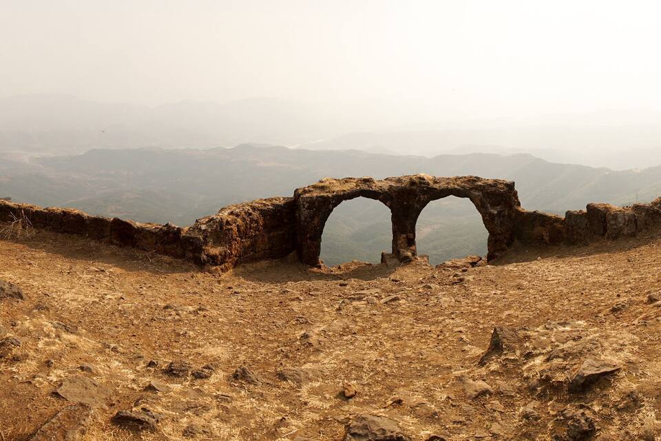 A rocky landscape with a large arch structure.