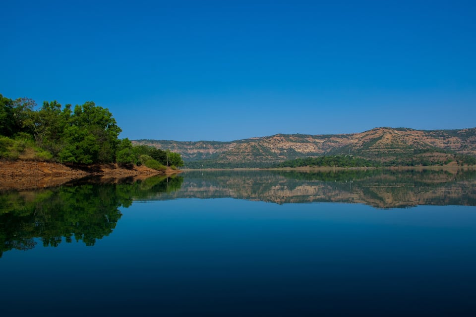 Un llac tranquil amb reflexos nítids dels turons i arbres circumdants.