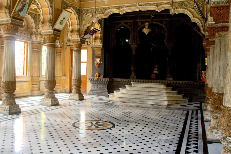 Un salón ornamentado con columnas intrincadas, un suelo estampado y un amplio vano oscuro.