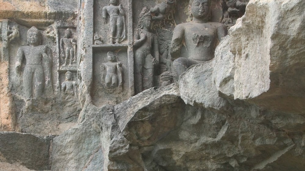 A detailed stone carving of a seated figure surrounded by smaller figures, likely depicting a historical or religious scene.