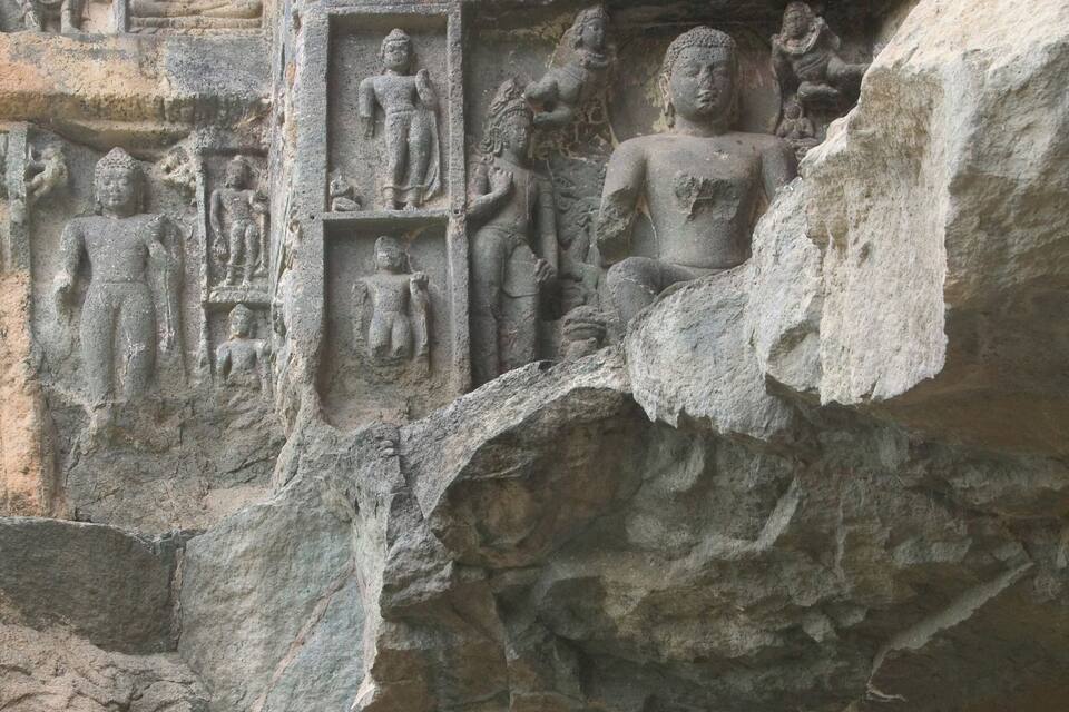 A detailed stone carving of a seated figure surrounded by smaller figures, likely depicting a historical or religious scene.