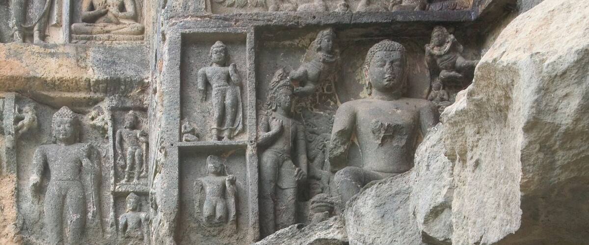 A detailed stone carving of a seated figure surrounded by smaller figures, likely depicting a historical or religious scene.
