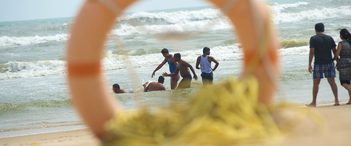 A lifeguard ring on a beach with people in the water and on the shore.