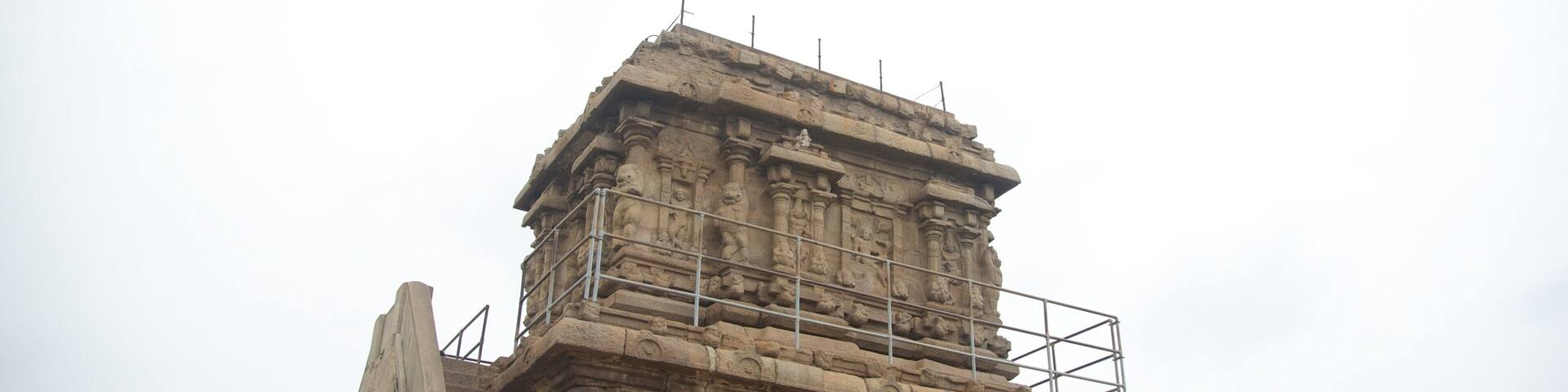 A stone temple with intricate carvings and a metal scaffold.