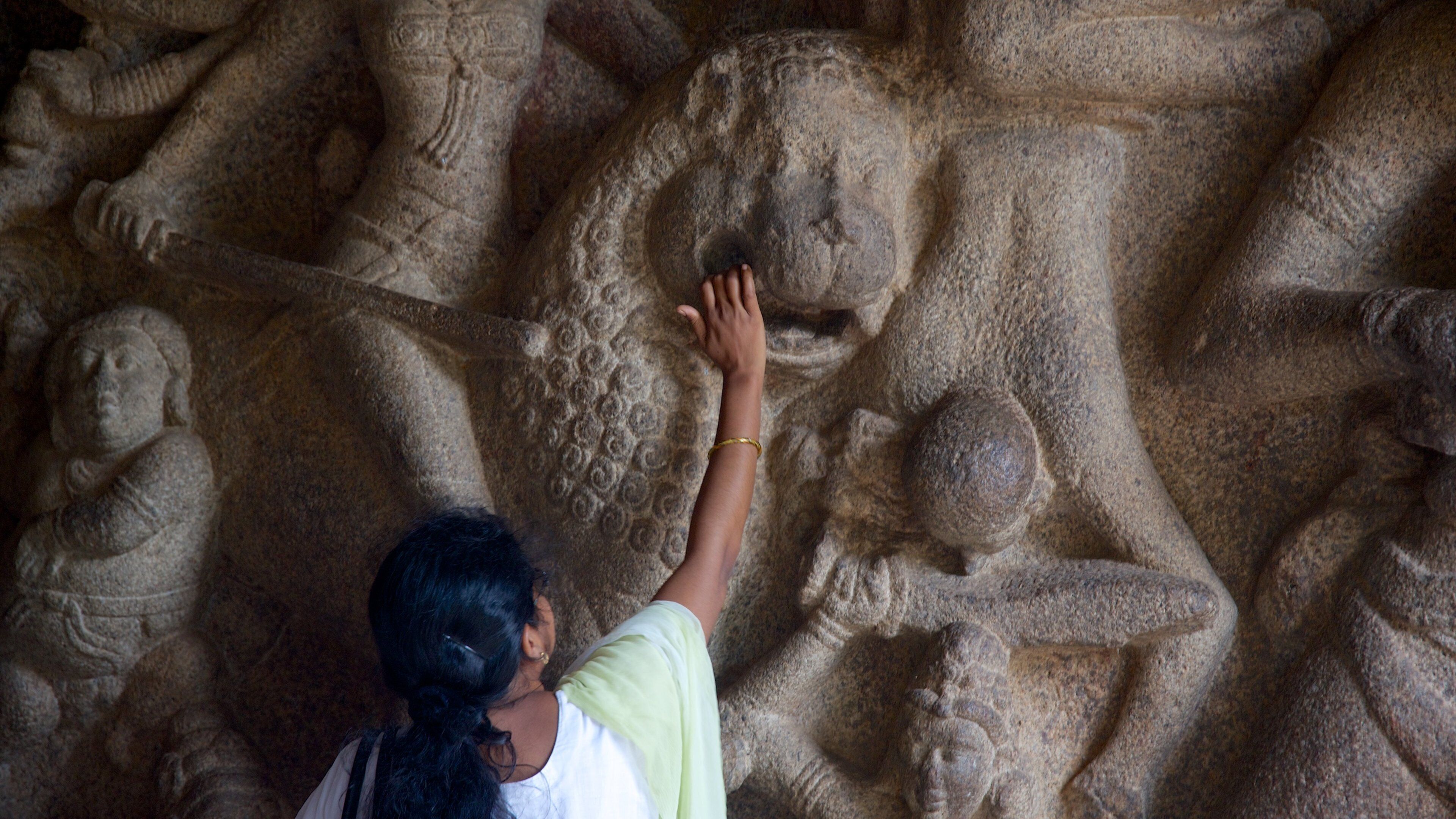 A person touching a stone sculpture.