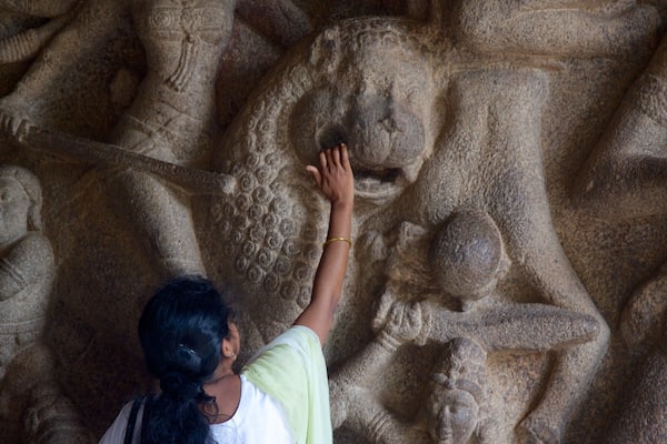 A person touching a stone sculpture.