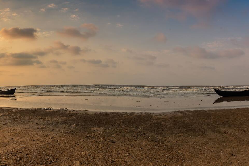 A beach with boats and a sunset.