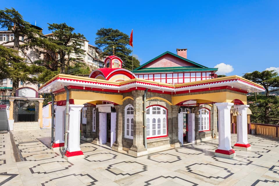A traditional building with a red roof, white columns, and patterned floor tiles.