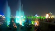Un spectacle nocturne de fontaines, avec des jets d’eau illuminés, et une pagode japonaise traditionnelle en arrière-plan.