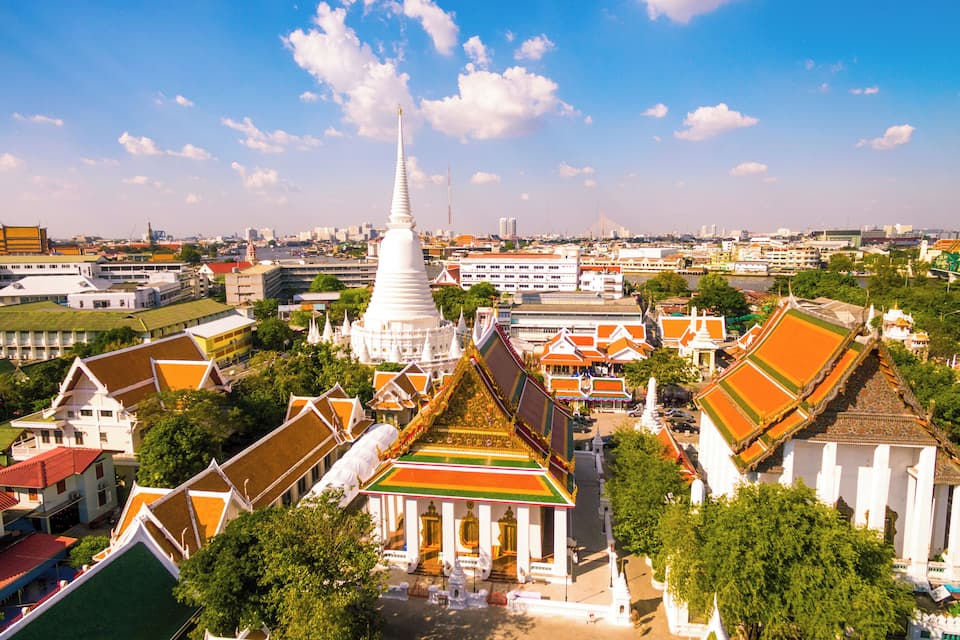 Een groot wit tempel met een hoge toren omgeven door traditionele gebouwen met kleurrijke daken.