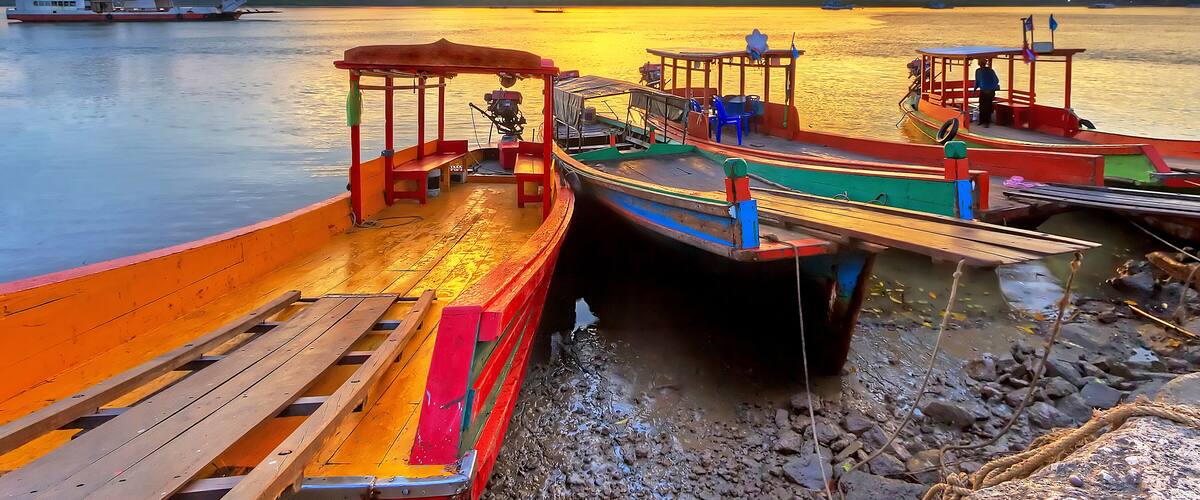A sunset over a calm river with boats docked along the shore.
