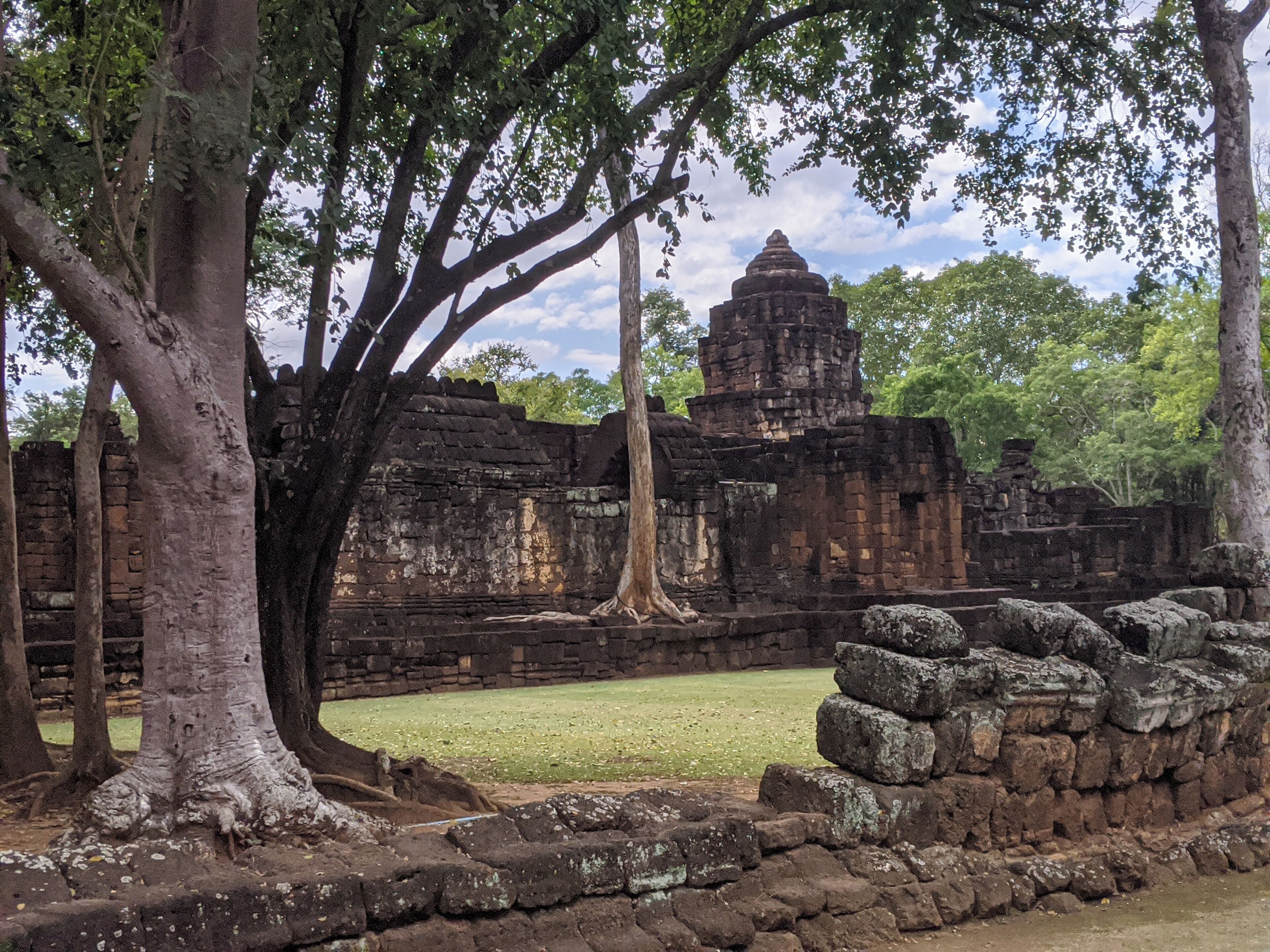 An ancient temple with large trees in the foreground and a clear sky in the background.