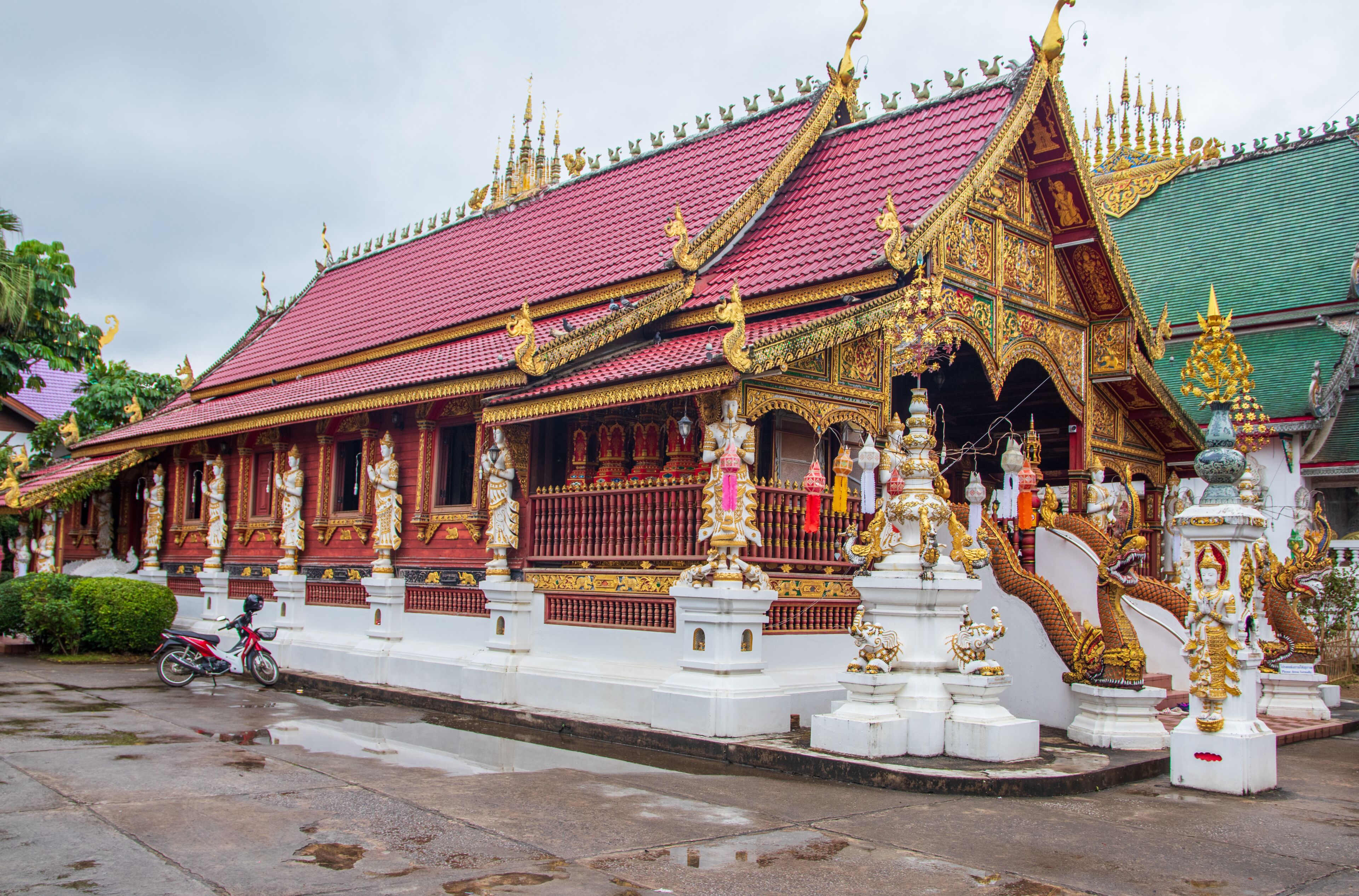 A traditional Thai temple with ornate golden decorations and a red roof.