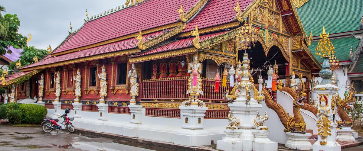 A traditional Thai temple with ornate golden decorations and a red roof.