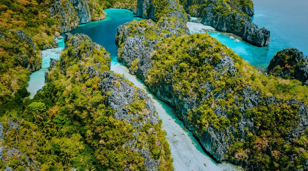 Aerial drone view beautiful shallow tropical Big and Small Lagoon explored inside by tourist on kayaks surrounded by jagged limestone karst cliffs. El Nido, Palawan Philippines