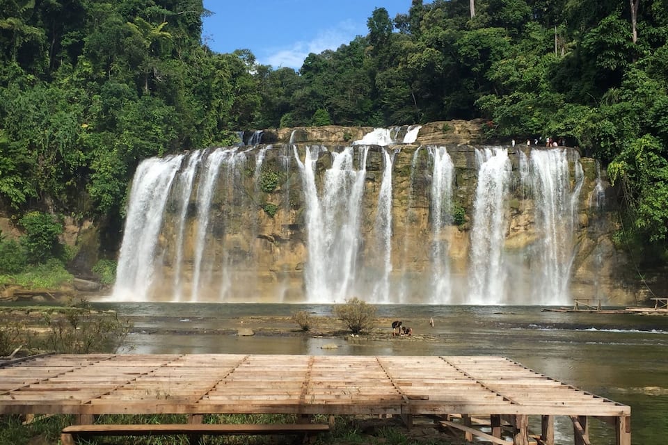 Ein mehrstufiger Wasserfall, umgeben von üppiger Vegetation.