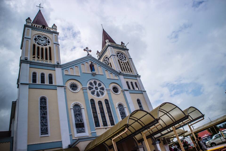 Une église dotée de deux tours, de grandes fenêtres circulaires et d’une girouette.