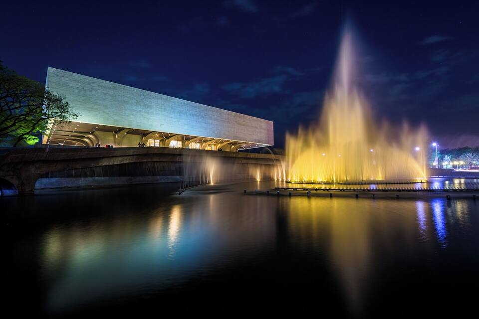 A modern building with a large water fountain in front.