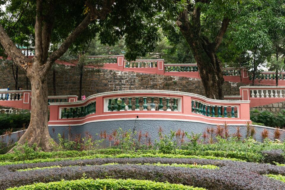 A landscaped garden with a curved pathway, trees, and a stone wall.