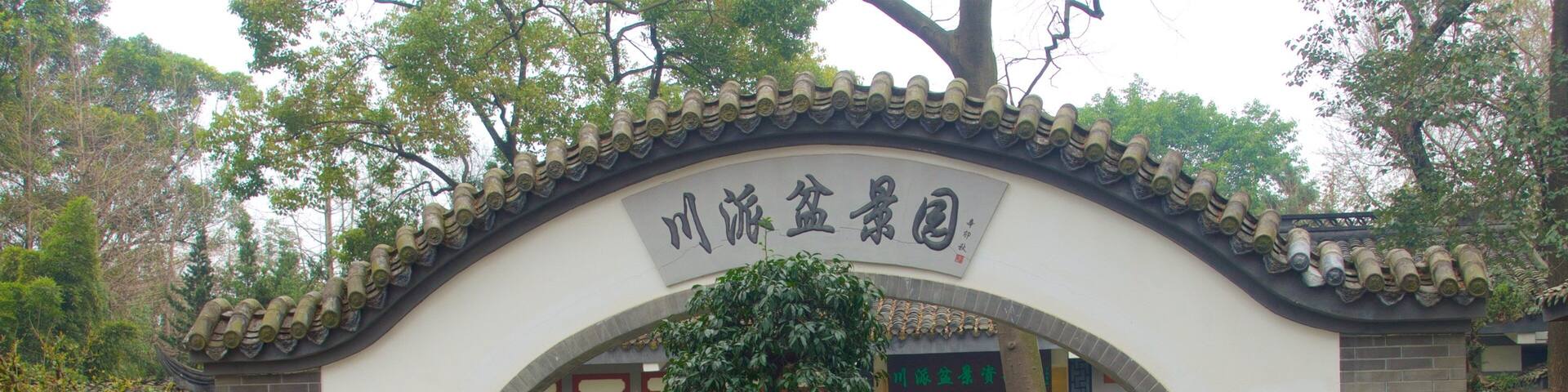 A traditional Chinese gate with a tree in the center, leading to a building with red doors.