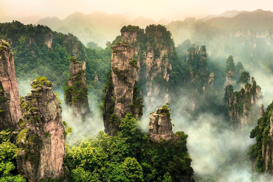 Towering limestone karst peaks, dense forest, and misty atmosphere.