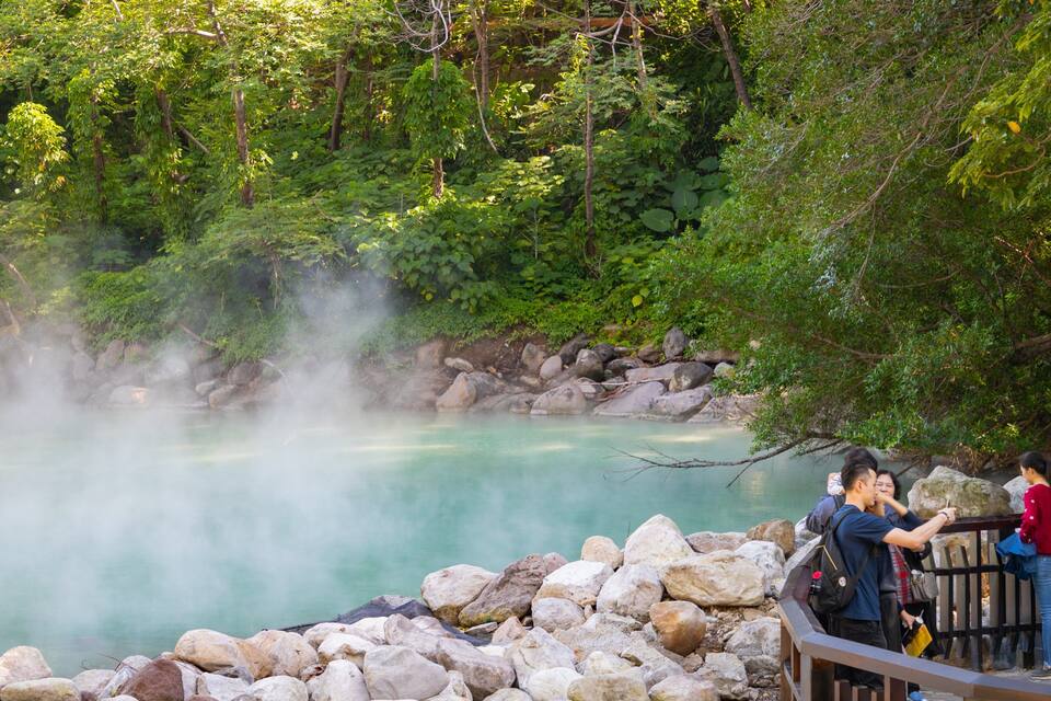 A hot spring surrounded by rocks and trees.