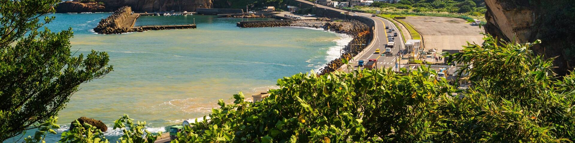 Un pueblo costero con playa, acantilados y una carretera que lleva al mar.