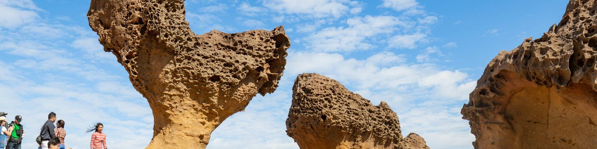 Un grupo de turistas frente a una formación rocosa con formas singulares.
