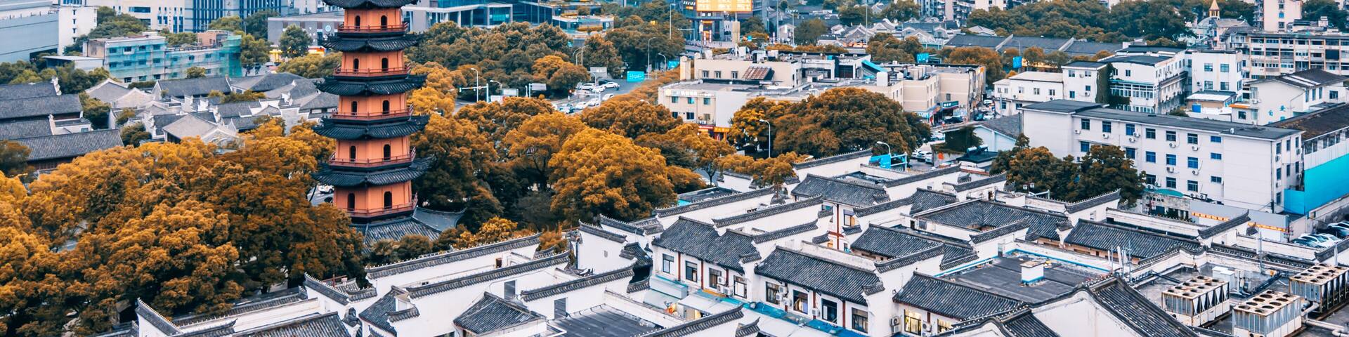 A traditional pagoda amidst a modern cityscape with high-rise buildings and dense urban architecture.