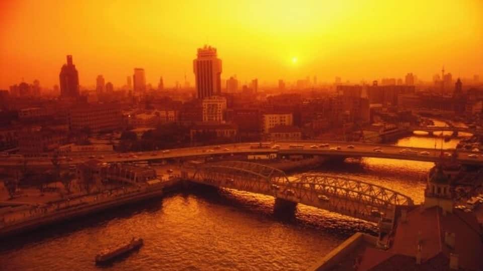Eine Stadtansicht mit einer markanten Brücke über einem Fluss, umgeben von Gebäuden und einem Sonnenuntergang.