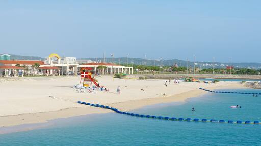 Okinawa showing swimming, a sandy beach and a coastal town