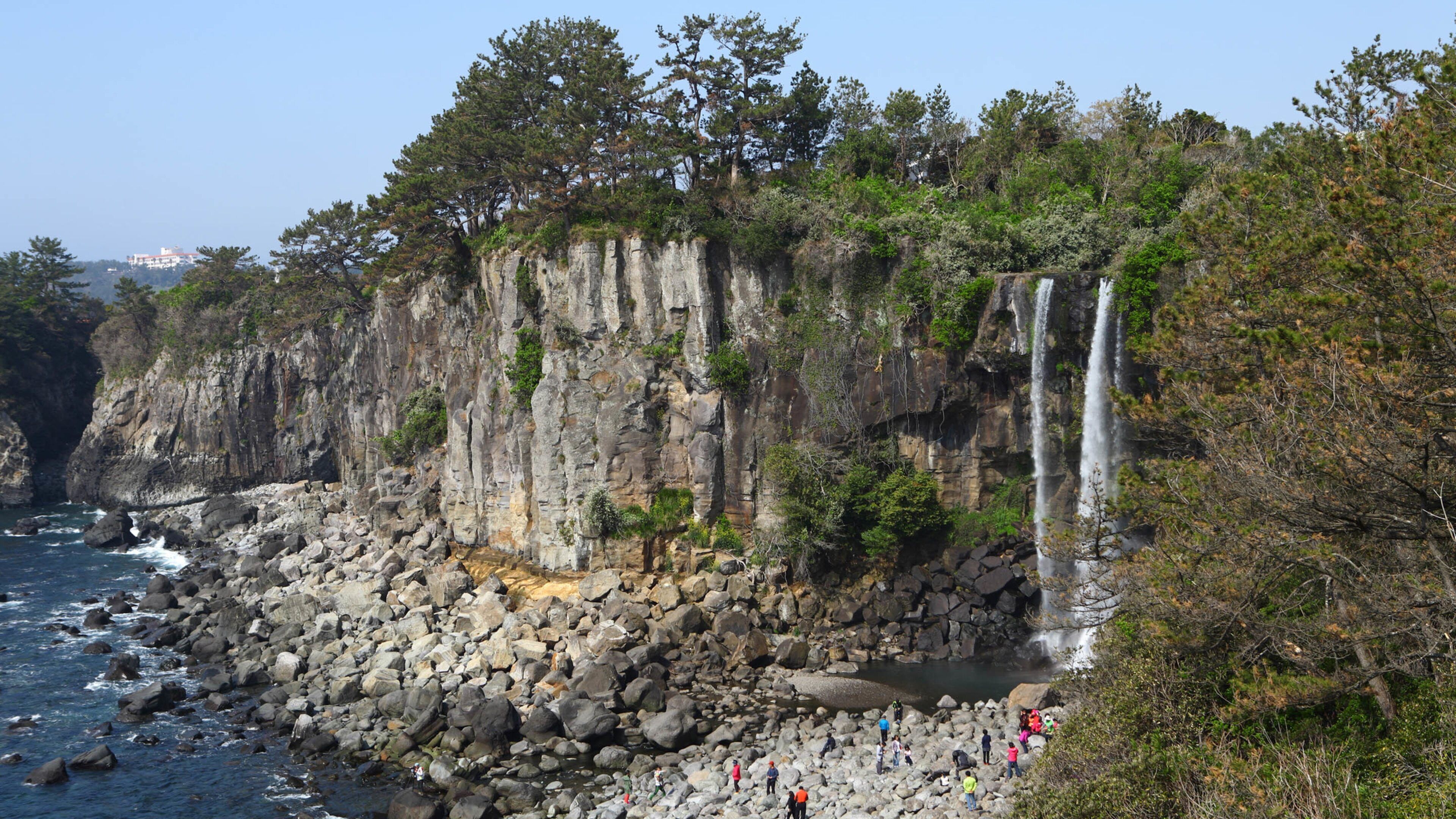 Jeongbang Waterfall which includes general coastal views, rugged coastline and a waterfall