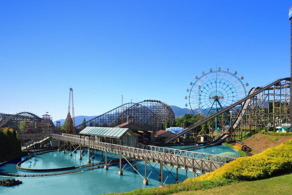 A roller coaster, a Ferris wheel, and a bridge over a body of water.