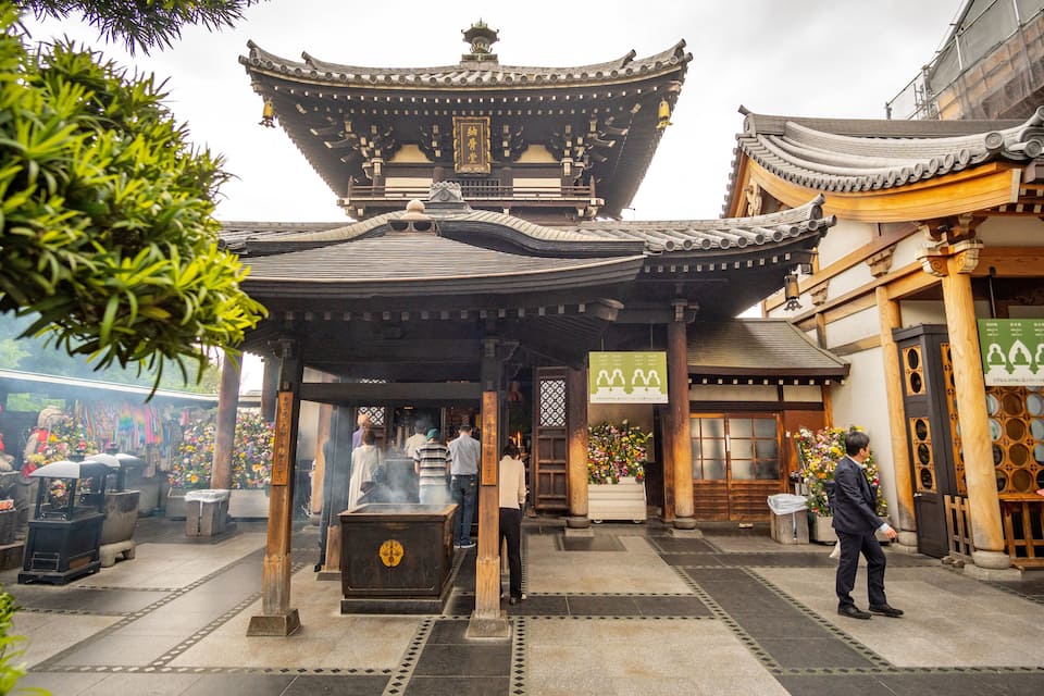 Un temple japonès tradicional amb una pagoda de diversos nivells, fanals de pedra i una estàtua de Buda de pedra.