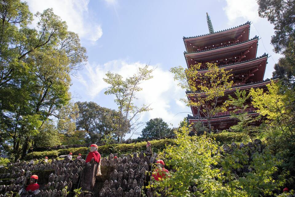 A traditional multi-tiered pagoda surrounded by lush greenery and stone lanterns.