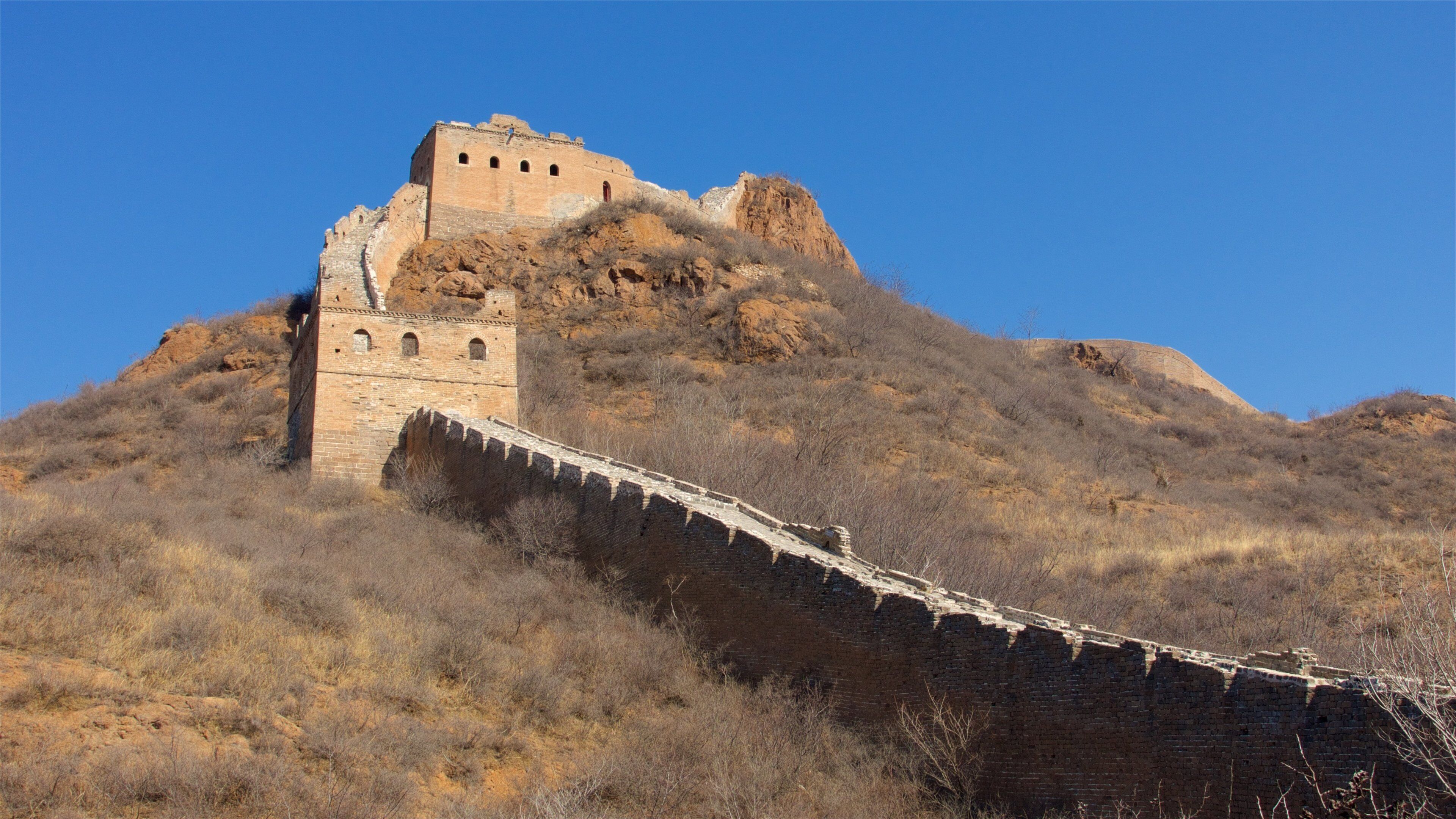 The Great Wall of China with a watchtower and a large fortification on a hill.