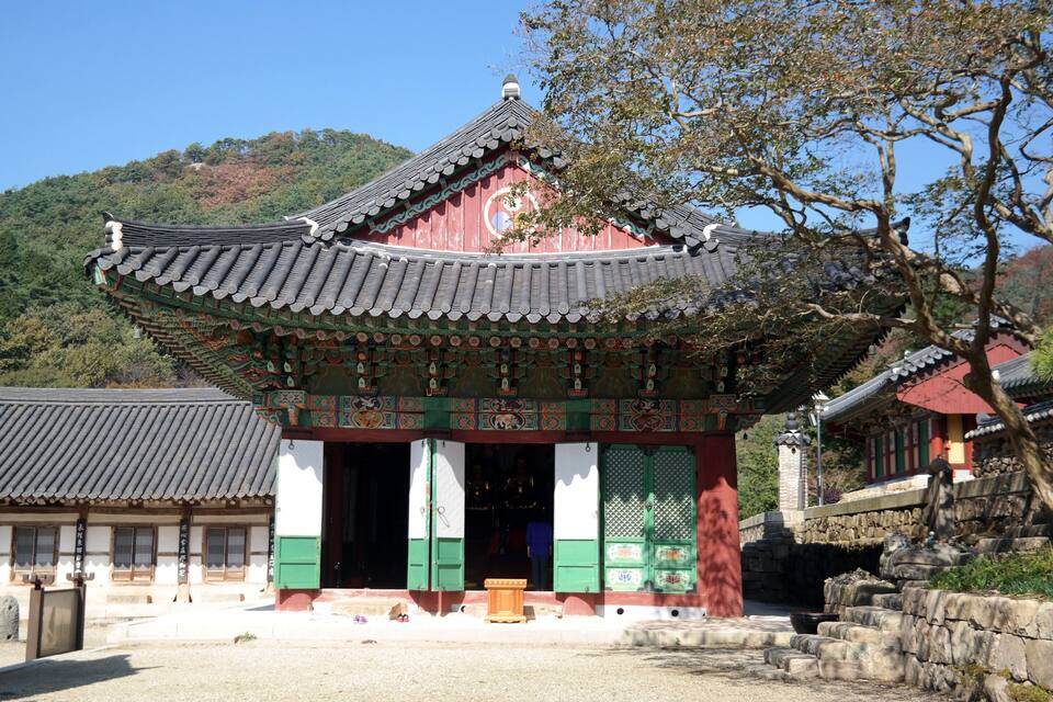 A traditional Korean building with a curved roof and green and white walls.