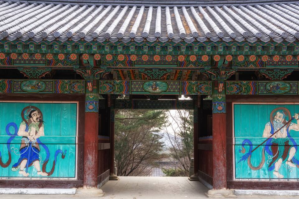 Una puerta coreana tradicional con pinturas elaboradas y un tejado de tejas.