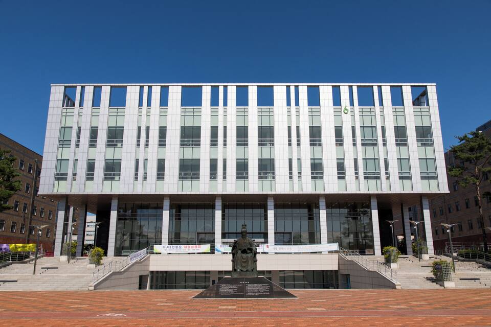 A modern building with large windows and a statue in front.