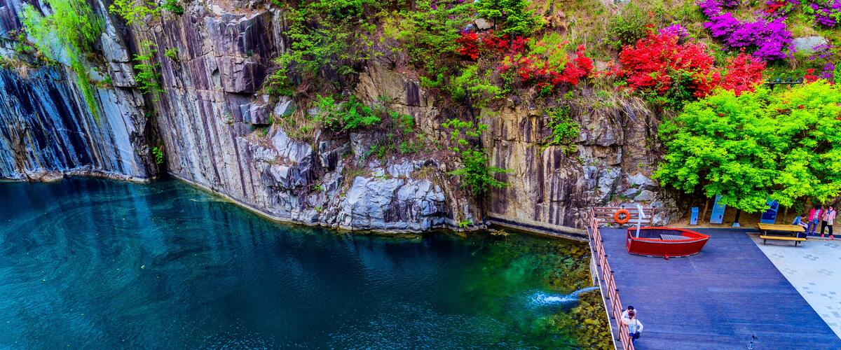 A clear blue water body, a wooden dock, and a red boat.