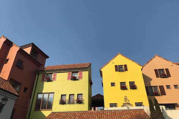 A row of colorful buildings with red-tiled roofs and flower boxes.