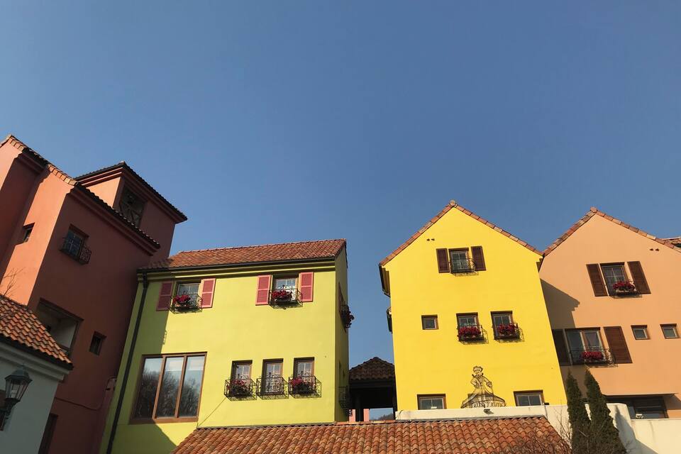 A row of colorful buildings with red-tiled roofs and flower boxes.