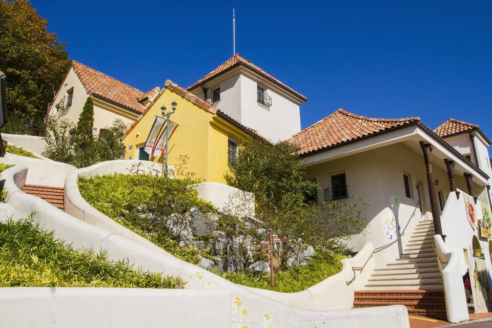 A hillside with a white building, a yellow building, and a red-tiled roof.