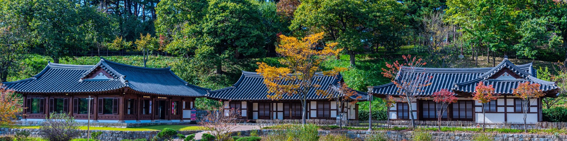 Arquitetura coreana tradicional com edifícios de madeira e um jardim bem cuidado.