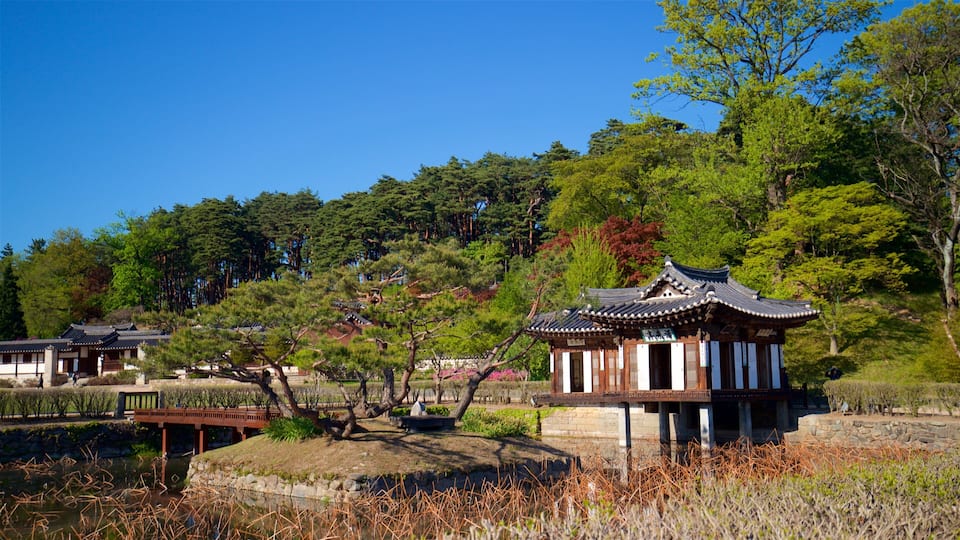 A traditional Korean pavilion surrounded by a pond, with trees and a clear blue sky in the background.