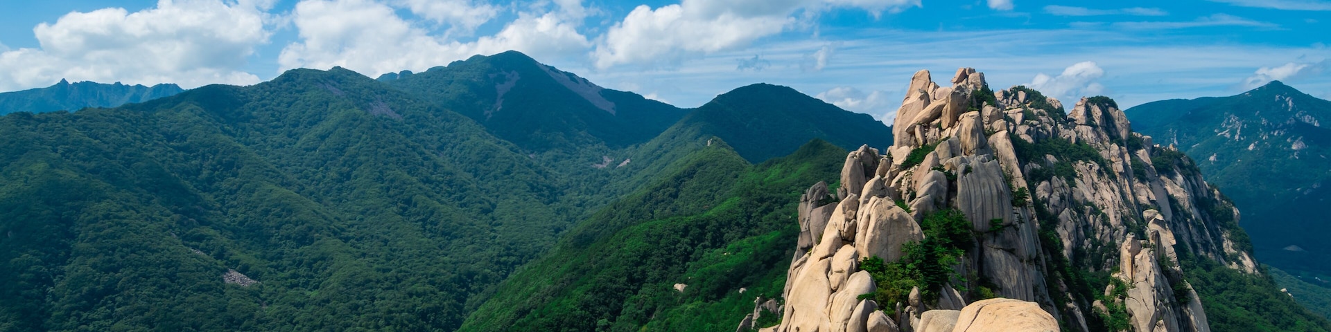 A mountainous landscape with a prominent rock formation and a red metal staircase.