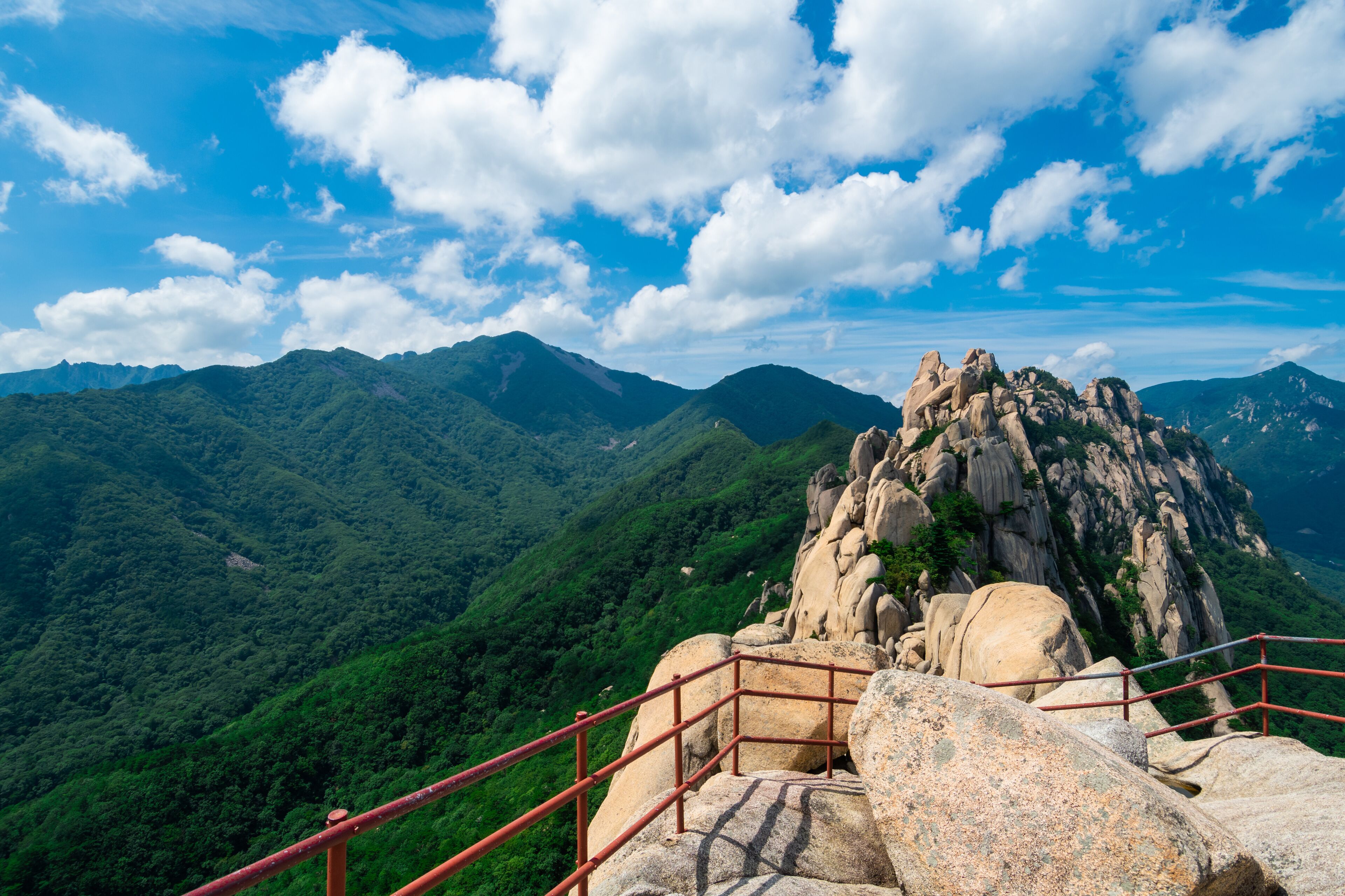 A mountainous landscape with a prominent rock formation and a red metal staircase.